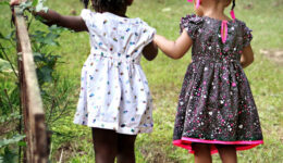 two little girls holding hands crossing bridge