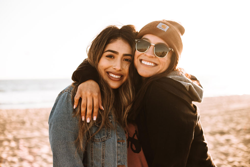 two friends hugging, on a beach background