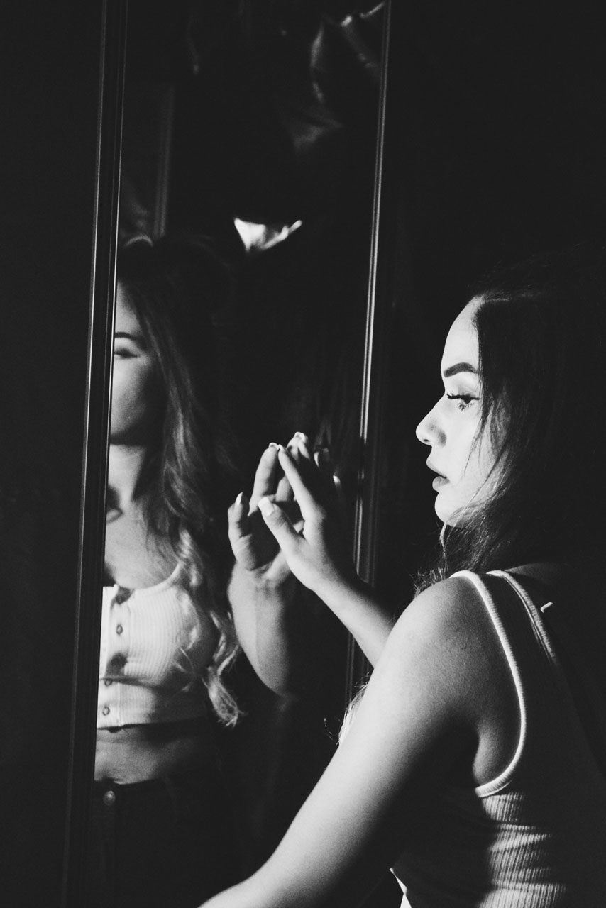 black and white image of girl looking in a mirror