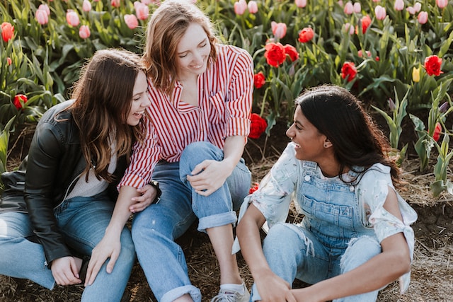 Talking things through for better mental health. Three teen girls chatting with a background of tulips Talking things through for better mental health. Three teen girls chatting with a background of tulips