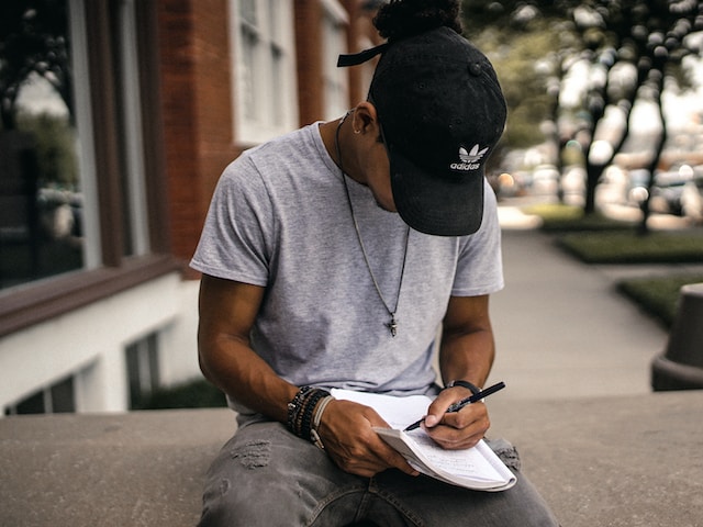 Journalling for better mental health. Teen boy in a cap writing in a journal Journalling for better mental health. Teen boy in a cap writing in a journal