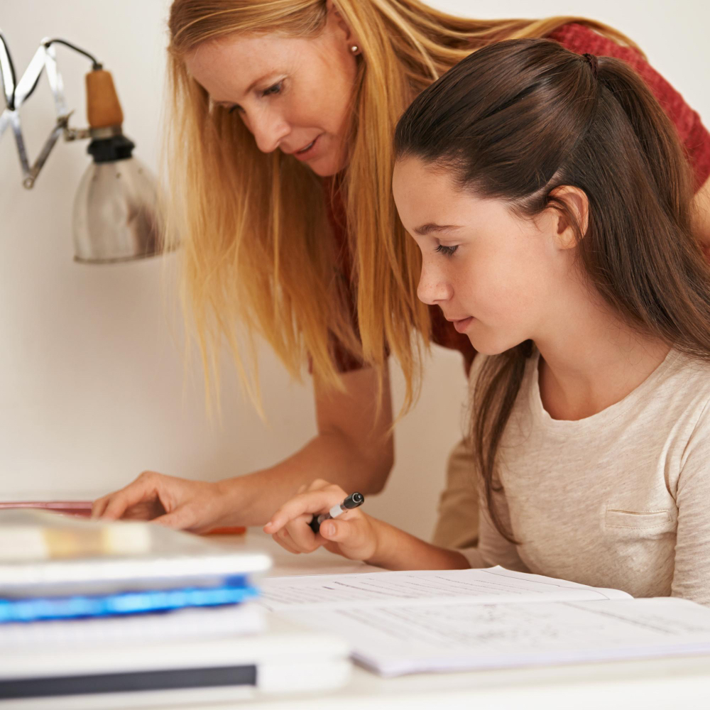 Mother helping teen study at a table